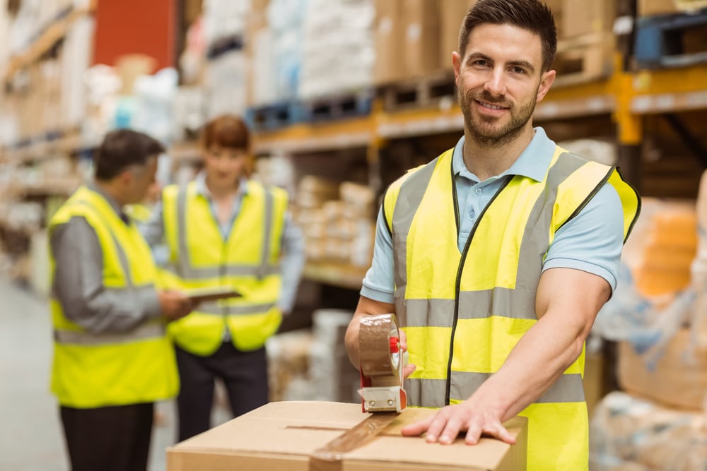 Smiling warehouse workers preparing a shipment in a large warehouse-1